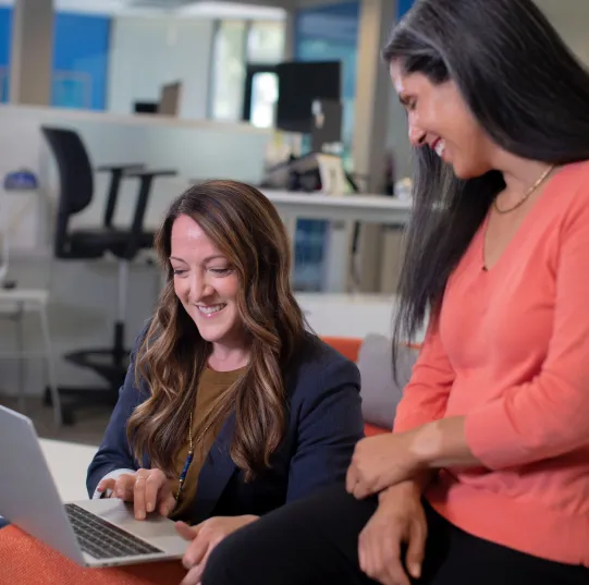 2 woman smiling and looking at laptop